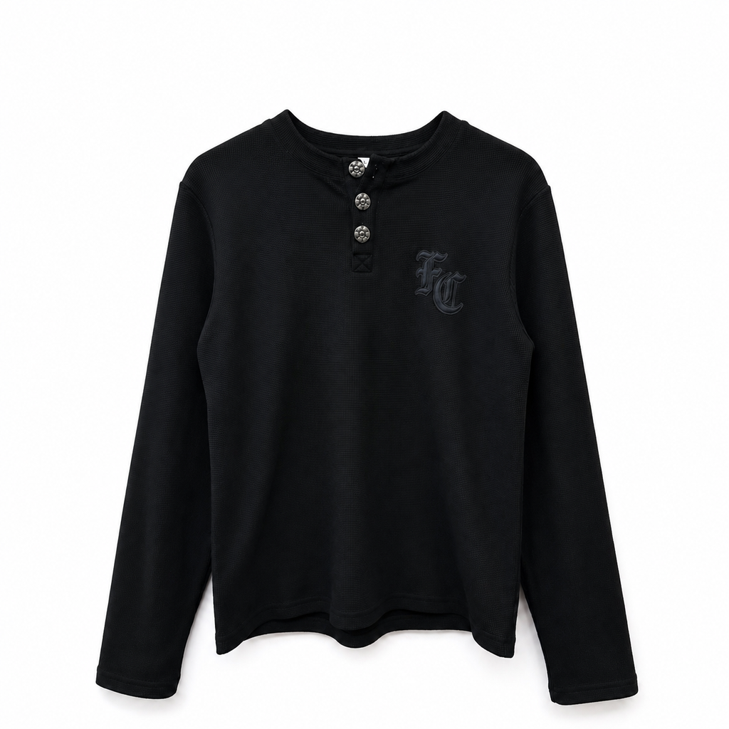 A black long-sleeve henley shirt with a three-button placket and a dark gray embroidered 'FC' logo on the left chest, displayed against a plain white background.